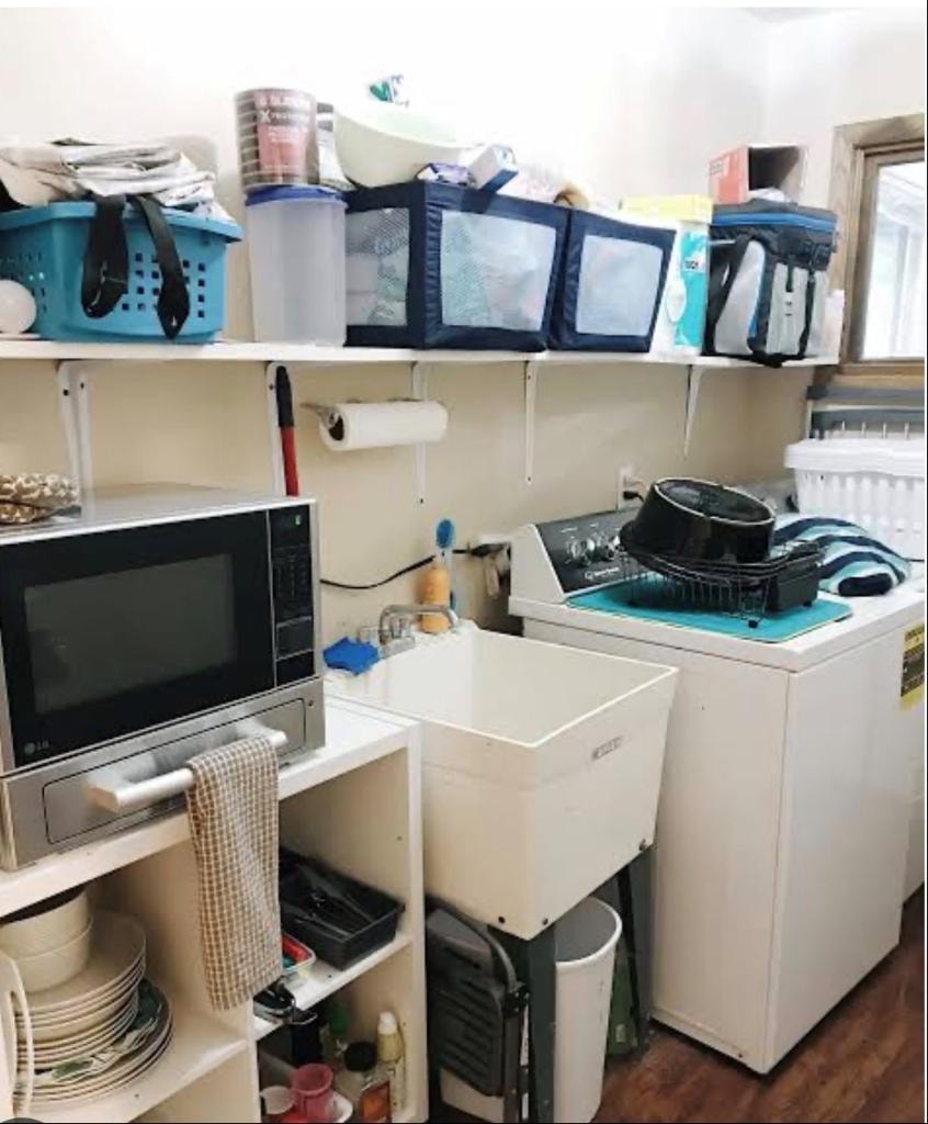 Microwave and dishes crammed into a laundry room as a temporary kitchen