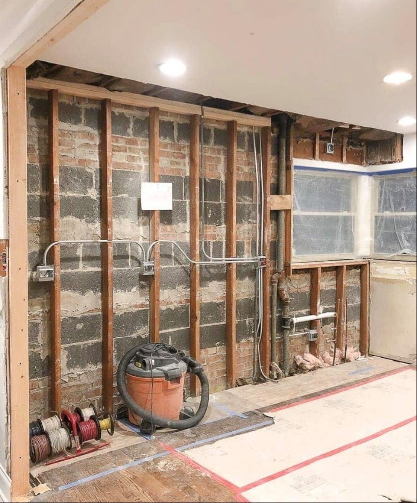 Kitchen gut renovation showing exposed brick and plumbing